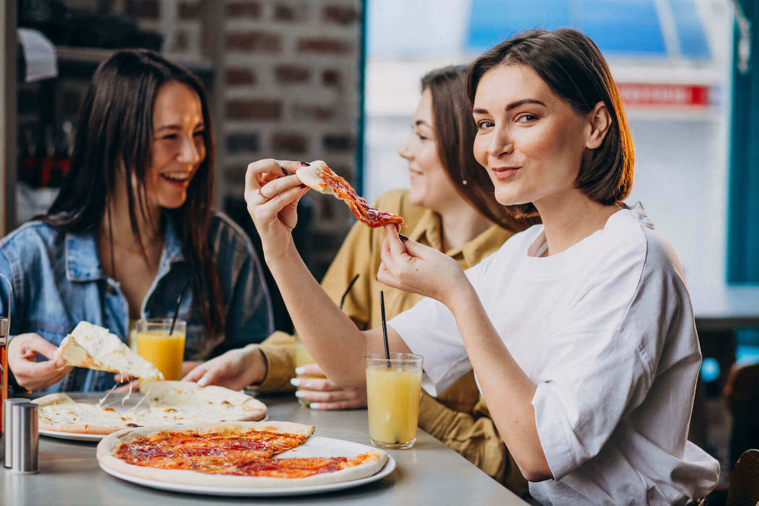 Three women eating a slice of pizza