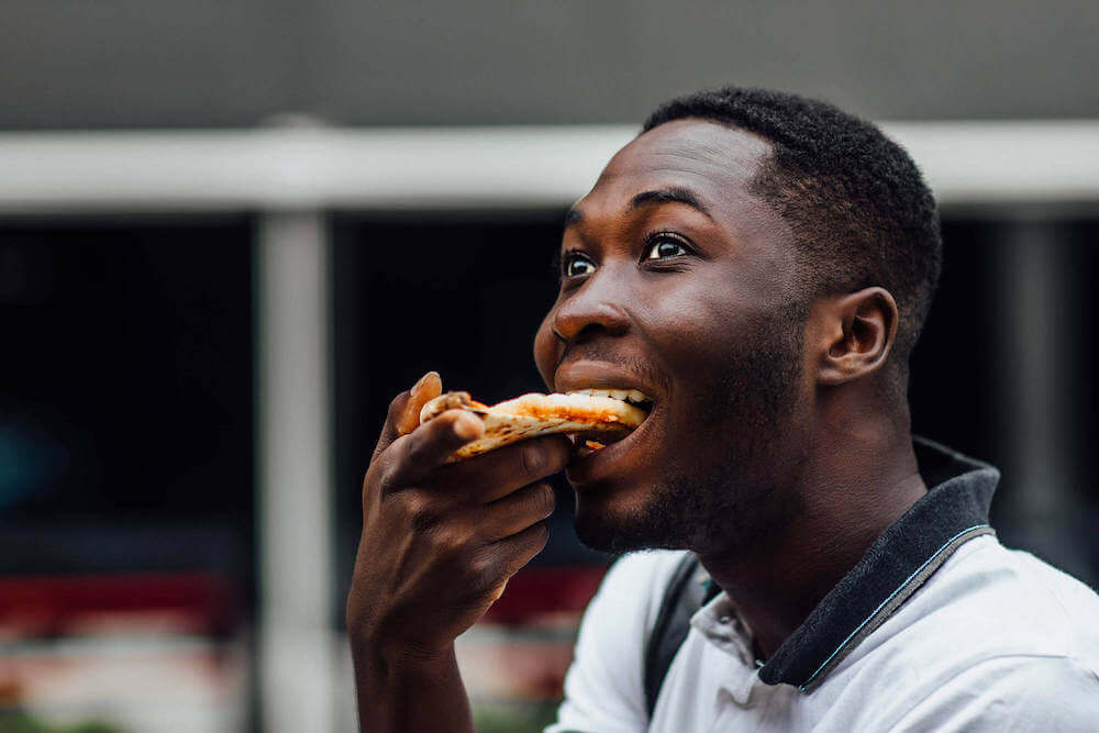 A hungry customer eating a slice of pizza