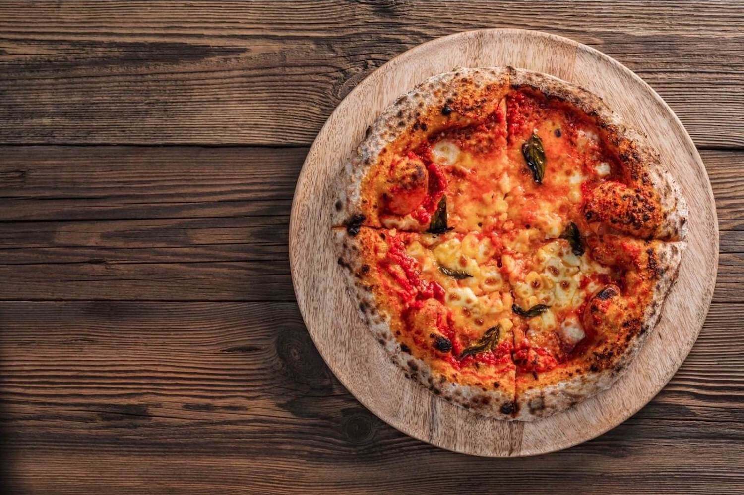 A wood cooked pizza on a chopping board