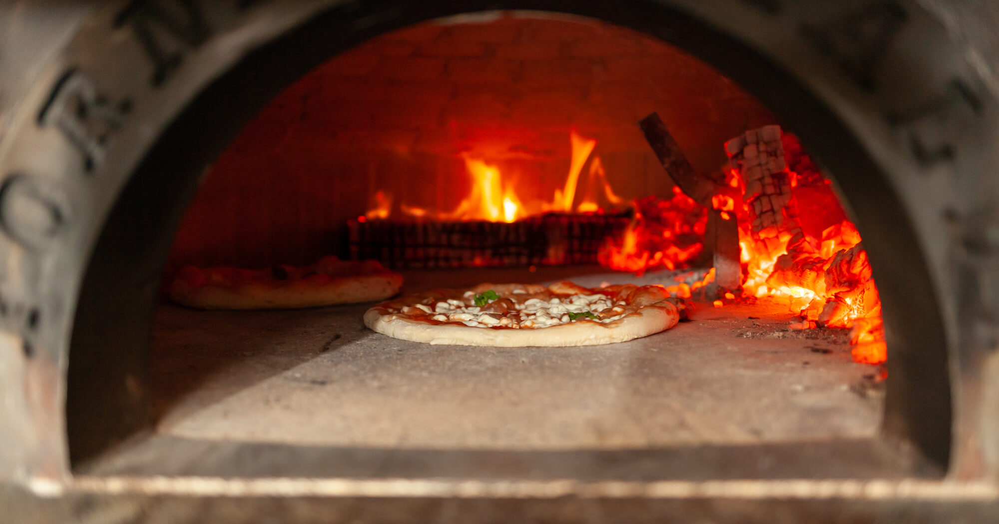 A wood fired oven with a pizza cooking on it