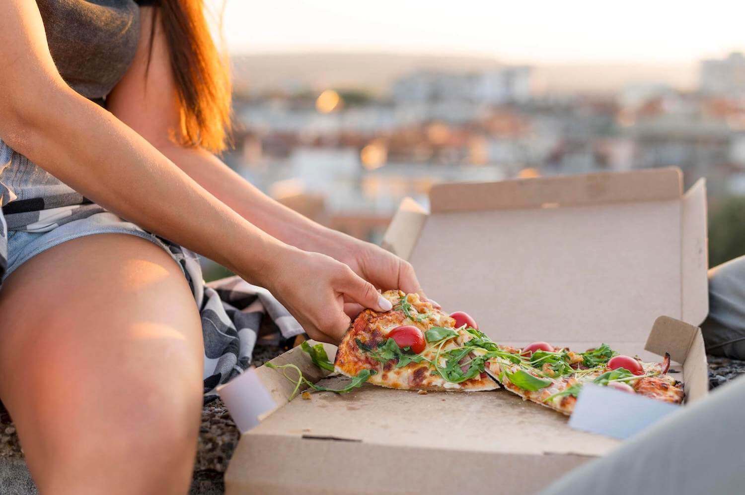 A customer next to a box of pizza outdoors